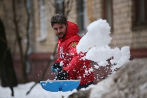 Муниципальный депутат Илья Свиридов убирает снег во дворе дома.
