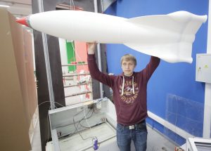 Инженер FabLab НИТУ МИСиС Михаил Михайлин с ракетой, сделанной на самом большом 3D-принтере в России (на заднем плане).