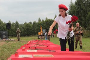 Волонтер Светлана Колесникова возлагает цветы перед захоронением 