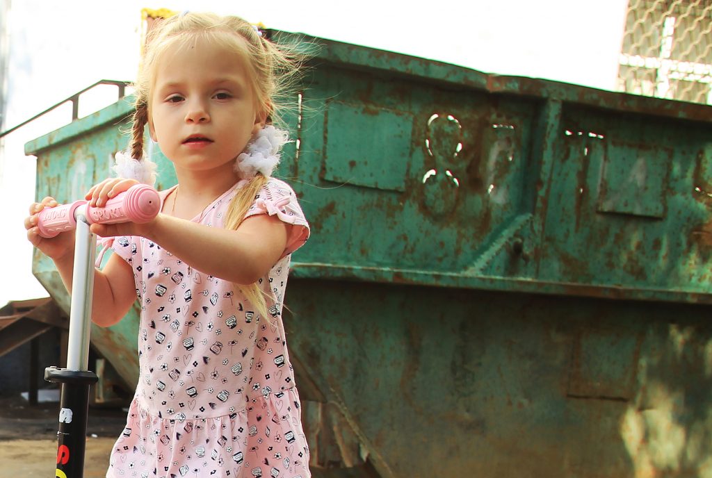 12 августа 2017 года. Настя Лысакова, катаясь на самокате, проезжает мимо мусорного контейнера, который расположен около детской площадки