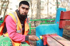 Рабочий Саиджон Батыев красит во дворе дома 24/28 на улице Красина лавочку и ограду. Фото: Наталия Нечаева,  «Вечерняя Москва»