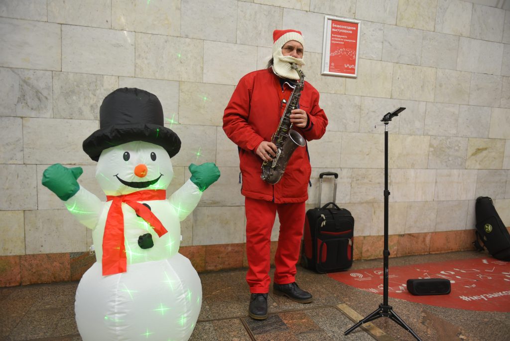 Саксофонист Антон Фоменко играет в переходе в компании с надувным снеговиком. Фото: Александр Кожохин, «Вечерняя Москва»