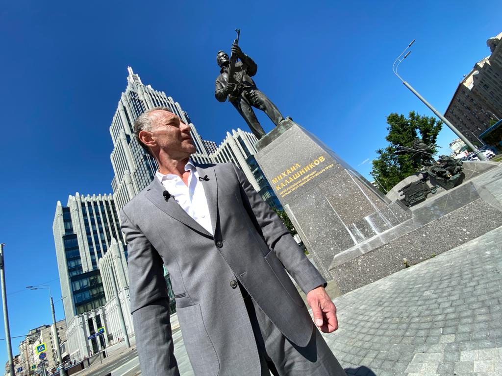 Ведущий Максим Дрозд на фоне памятника Калашникову. Фото предоставили в ГБУ «Центр»
