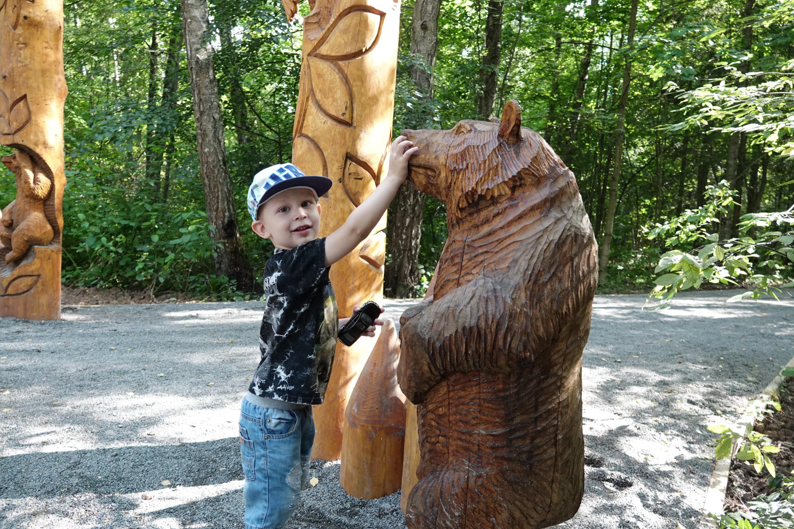 26 июля 2019 года. Юный житель поселения Московский Матвей Бурлак знакомится с деревянным медведем на экотропе.Фото: Виктор Хабаров