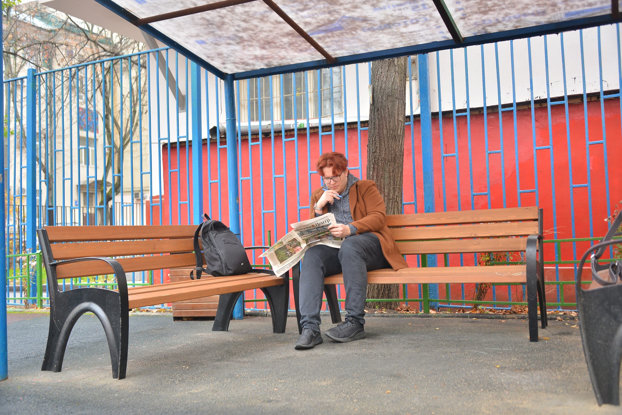 Житель дома № 5/20 в 1-м Басманном переулке Антон Марченко читает газету «Москва.Центр» на новой лавочке у себя во дворе. Фото: Анна Малакмадзе, «Вечерняя Москва»